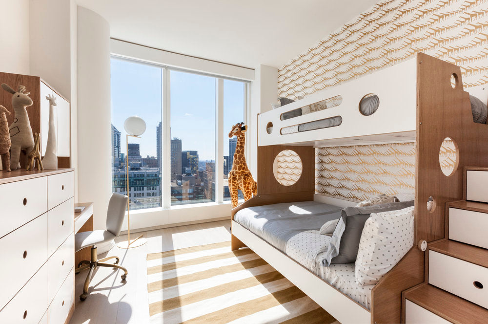 Modern bedroom with bunk bed, desk, and large window overlooking city.