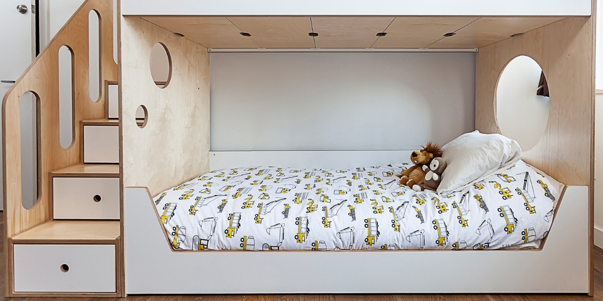 Custom child's bed nook with steps, built-in storage, and a playful animal-themed bedspread.