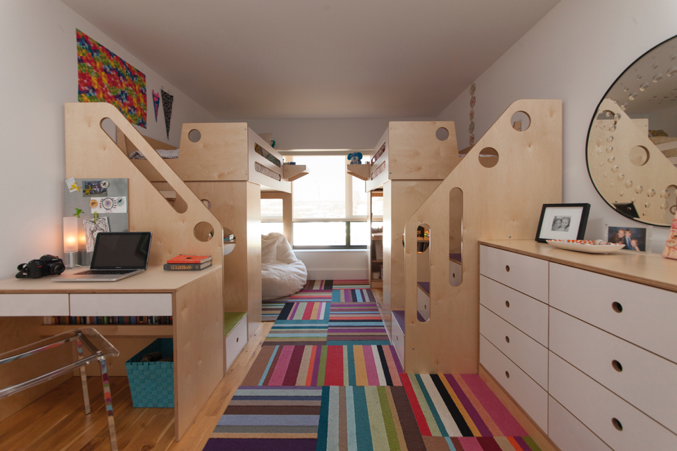 Stylish modern bedroom with bunk beds, desk, computer, colorful rug, and wall art.