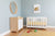A modern baby's room with a crib, dresser, and toys on a rug, under an elephant picture
