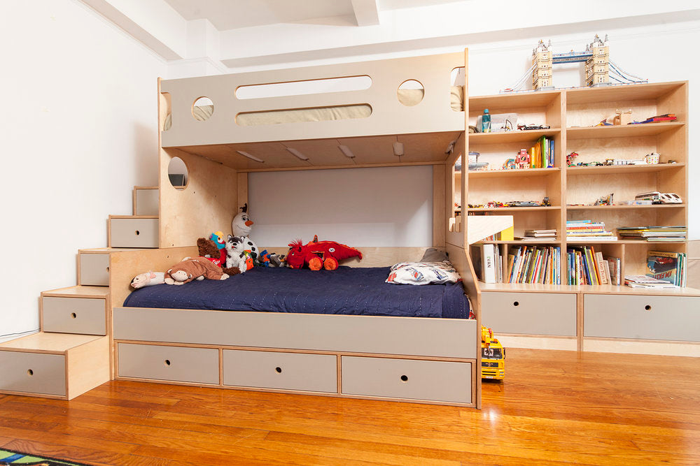 Bedroom with wooden bunk bed, storage, and bookshelves.