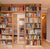 Wooden bookshelf wall filled with colorful books, featuring a mirrored door, in a cozy reading nook.