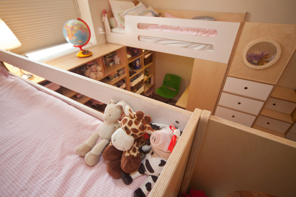 A well-organized child’s room with a pink bed, stuffed animals, a globe, and neatly arranged shelves.