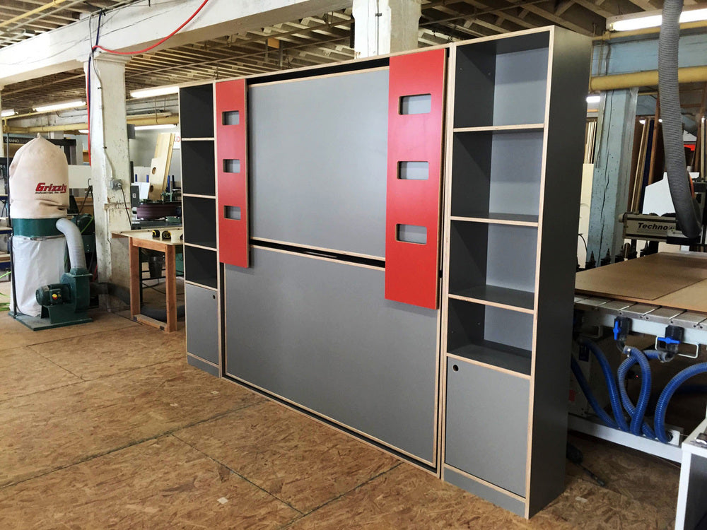 Modular storage unit in workshop: grey and red panels, shelves, drawers. Industrial ambiance.