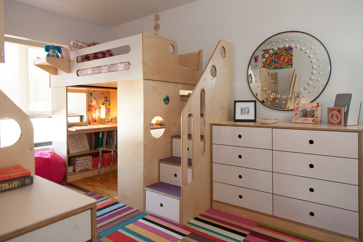 Child’s room with loft bed, desk, and colorful rug.