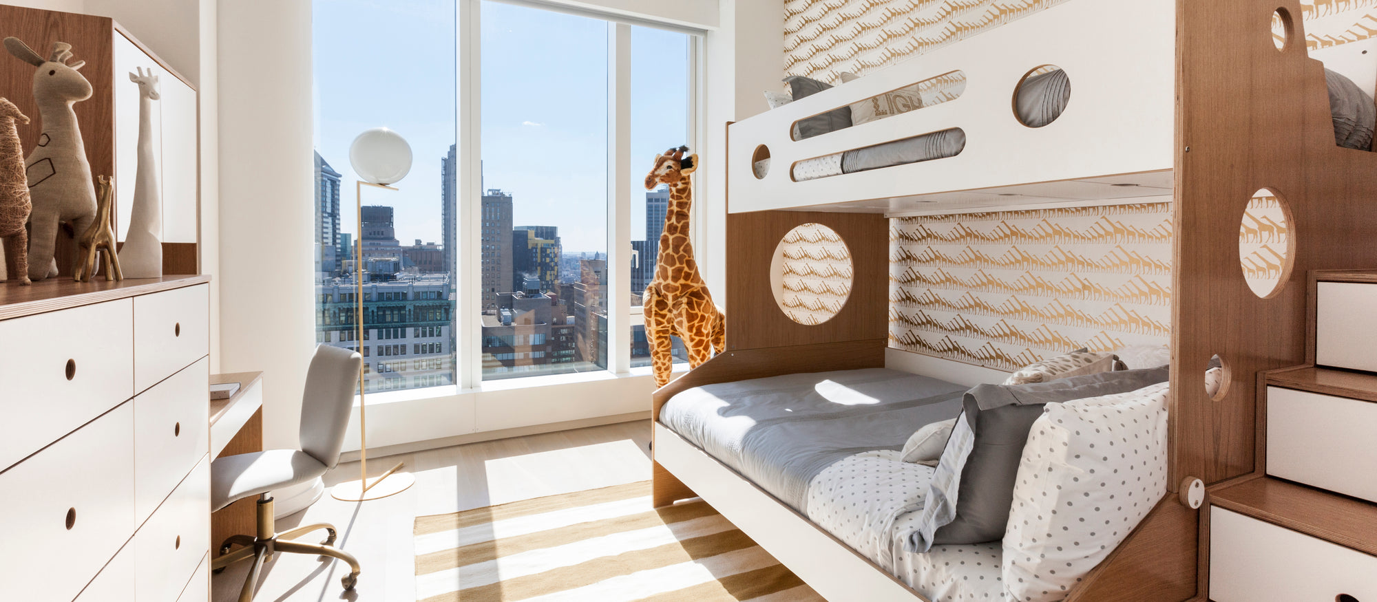 Modern children's room with wooden murphy bed, built-in storage, large windows overlooking the city.