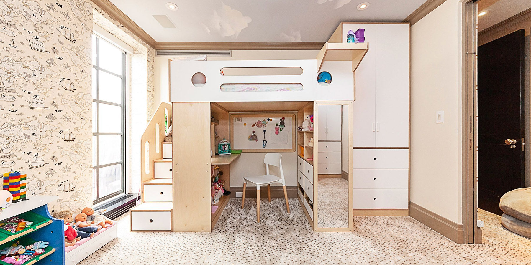 Spacious children's room featuring a custom house-shaped bunk bed with a study area and playful wallpaper.