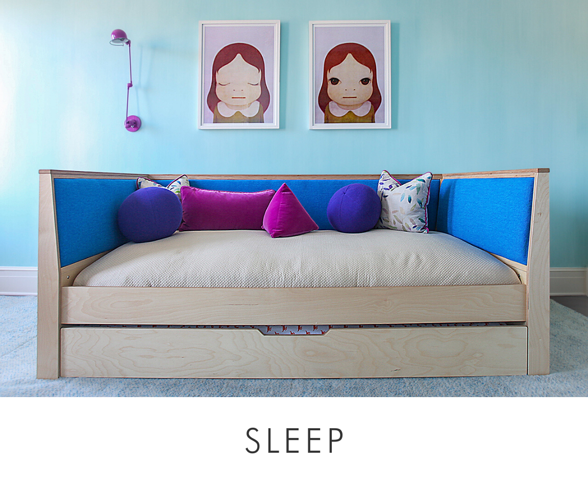 Contemporary wooden bed with blue headboard, colorful cushions, and two quirky portrait artworks above.