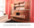 Converted workspace room , compact home office with a floating wooden desk, built-in shelves, and coral pink walls.