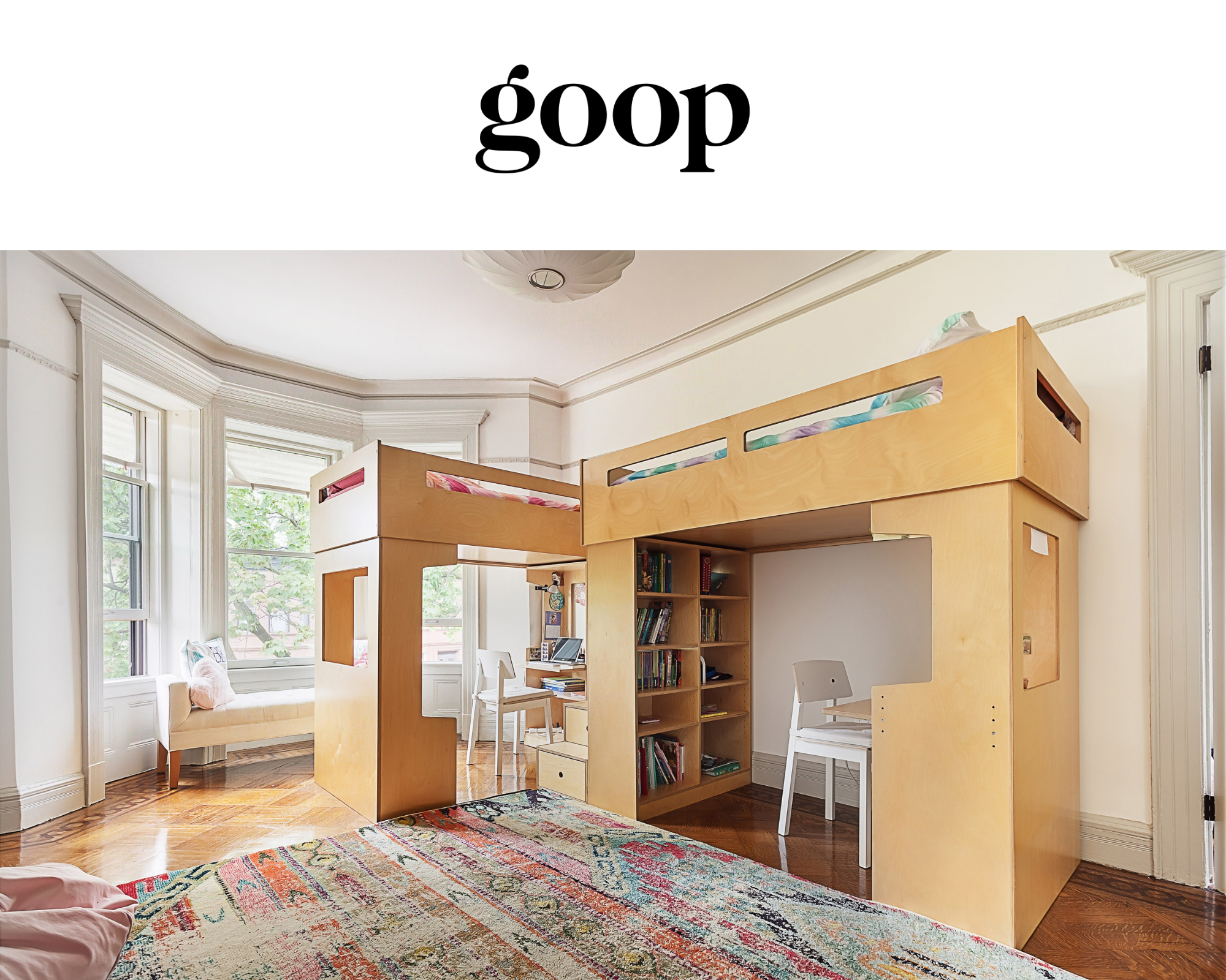 Room with bed, rug, loft with desk, shelves, and “goop” sign.