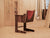 Stylish dark wooden chair with a red leather backrest set in a plywood workshop environment.