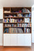 Bookshelf with books, records, and decor in a cozy room.
