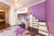 Kids' room with a purple theme, bunk bed with stairs, desk under the bed, storage, and a rug with large purple flowers.