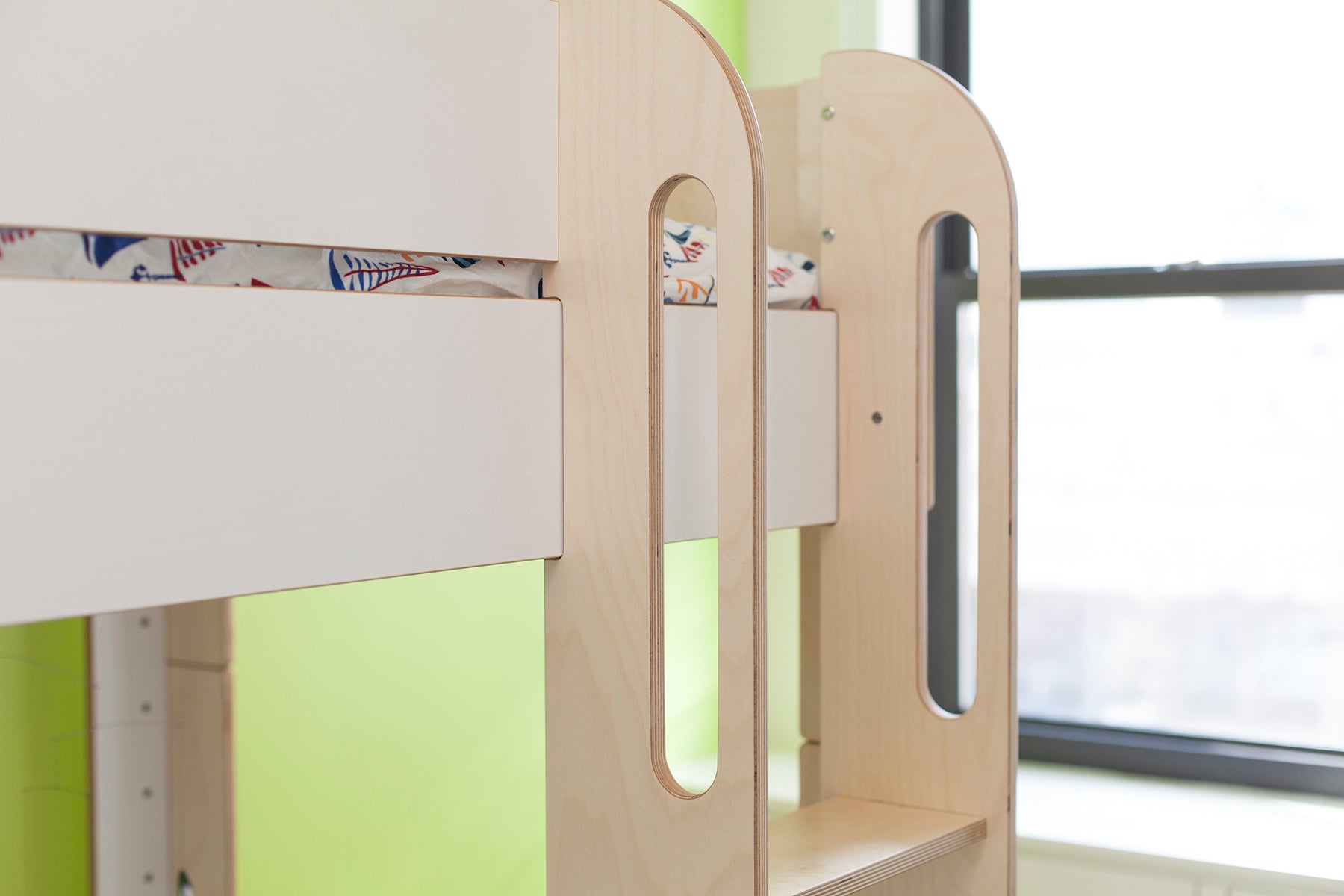 Indoor wooden play structure with green accents by a window.