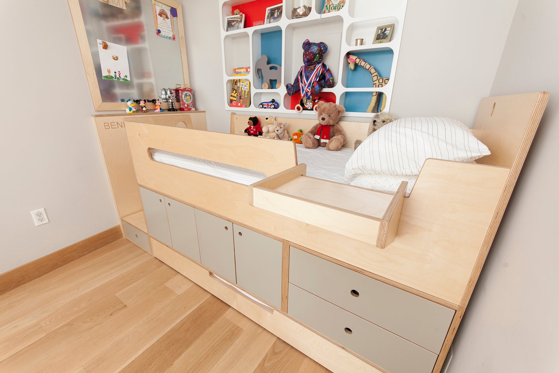 Wooden bed with storage and toys in a child’s room.