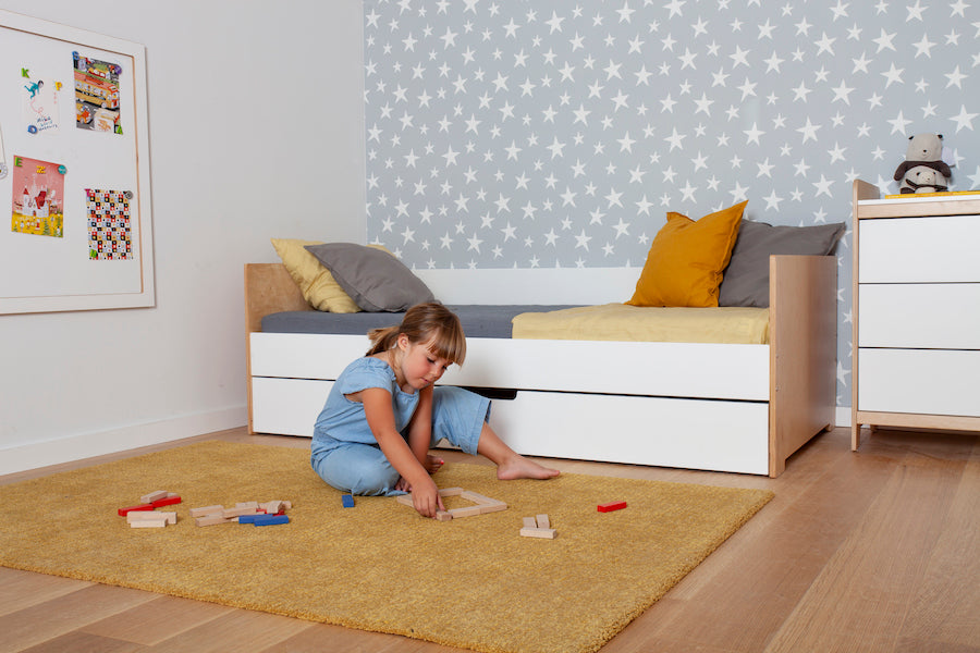 Child playing with colorful blocks on the floor in a clean, bright room.