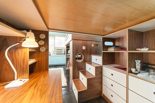 Sleek, modern study area with rich wooden paneling, stylish drawers, and an elegant desk lamp.