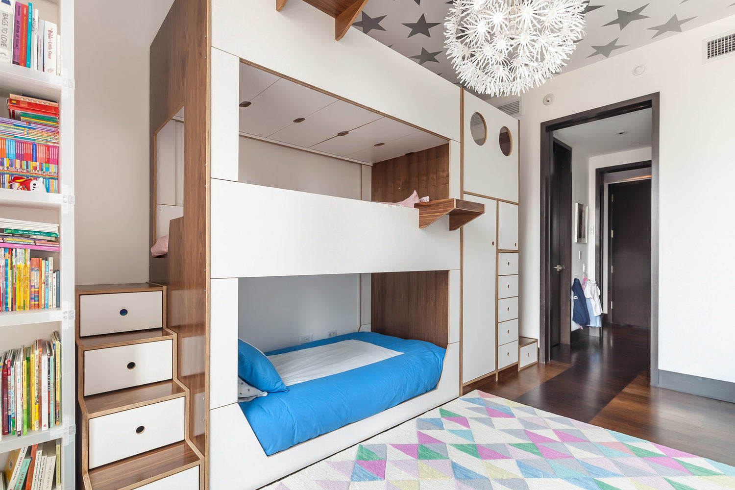 Modern children's bedroom with built-in bunk beds, colorful rug, and star-patterned ceiling.