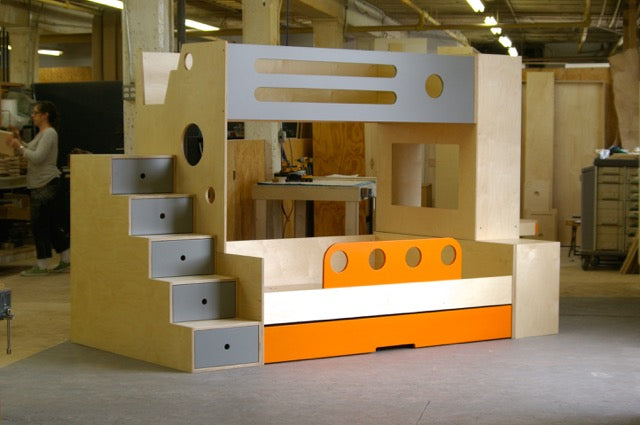 A wooden bunk bed designed like a ship with built-in stairs and storage.