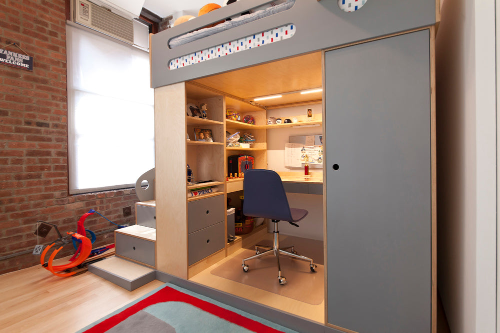 A cozy office with desk, chair, shelves, and a red scooter outside.