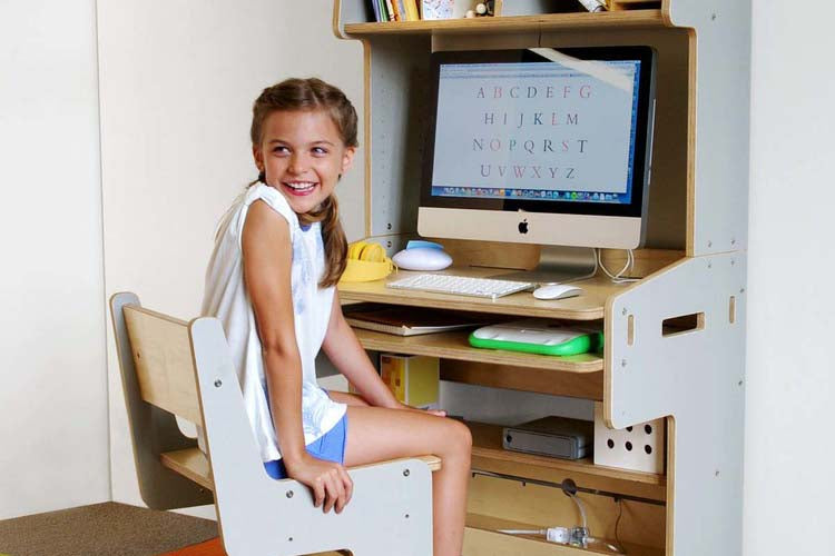 Person at computer desk, face obscured, screen with text.