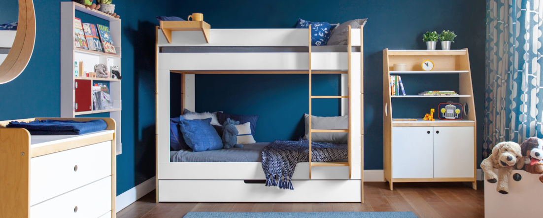 White and birch bunk bed in navy room with dark wood floor, blue rug, and grey bedding with white wall frames