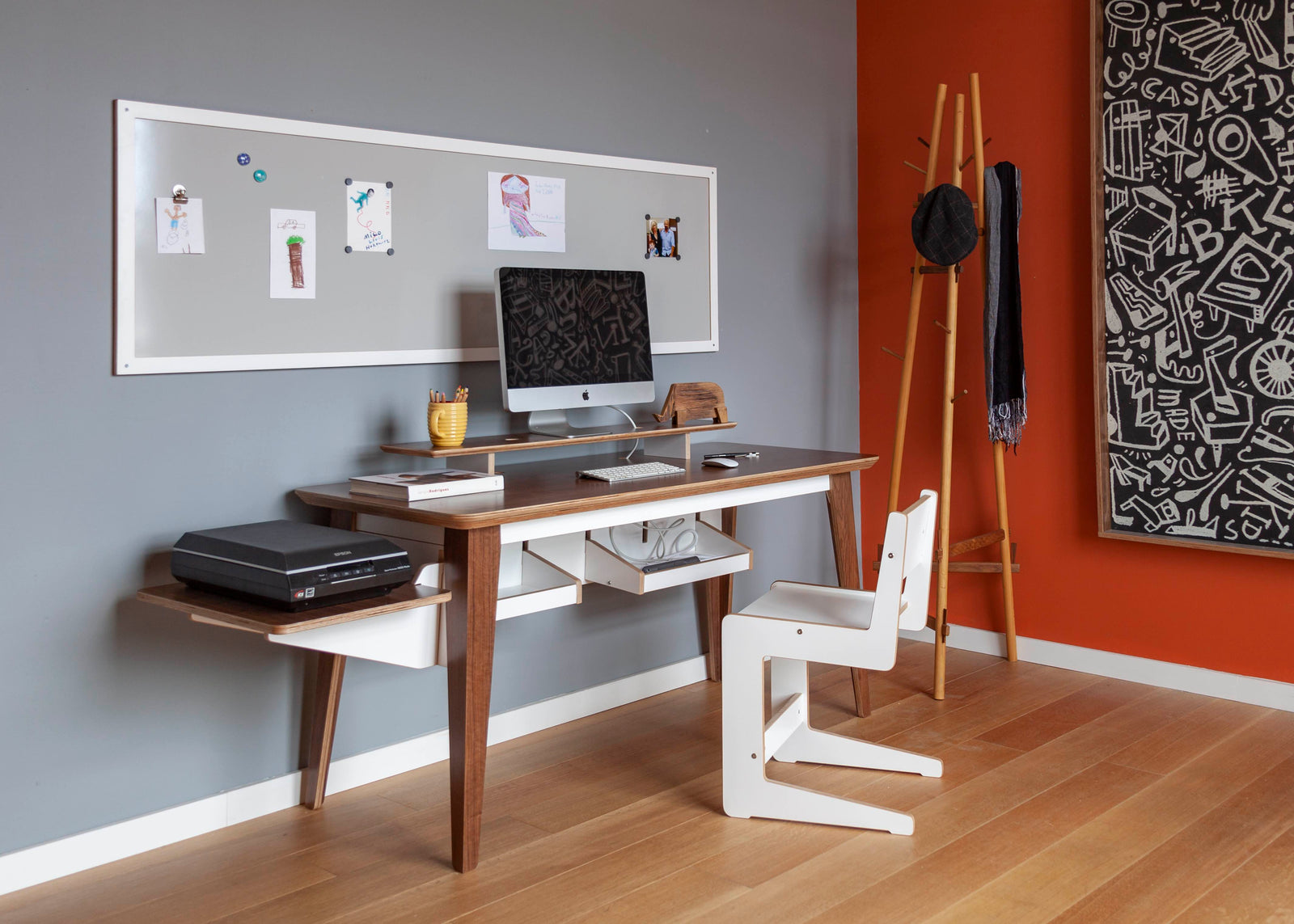 Stylish home office with wooden desk, ergonomic chair, terracotta walls, and a large monochrome art.
