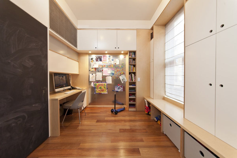 Bright study room with built-in desks and cabinetry, hardwood floors, and a large window for natural light.
