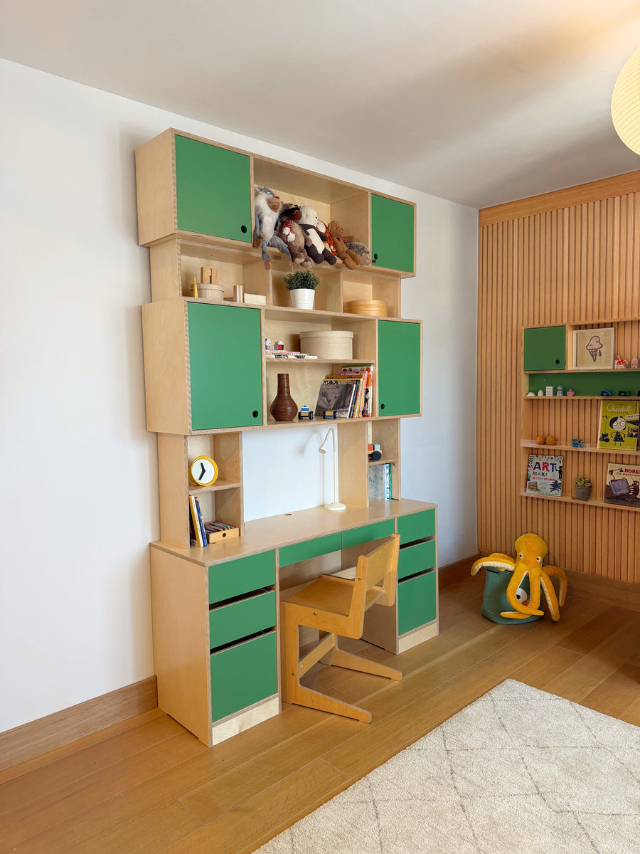 Green hutch desk with matching chair in light wood kid's room with embedded wall shelf and toys.