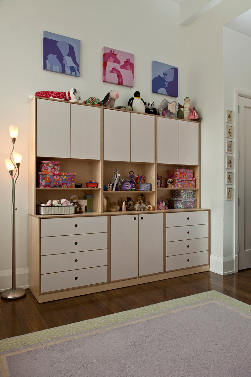 Storage unit with toys, animal art, and a lamp in a child’s room.