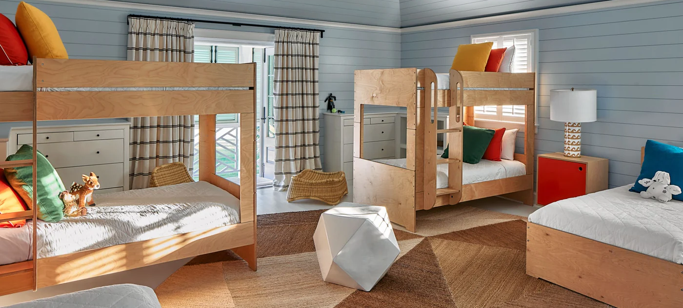 Spacious children's bedroom with twin bunk beds, individual bedding styles, and serene blue walls.
