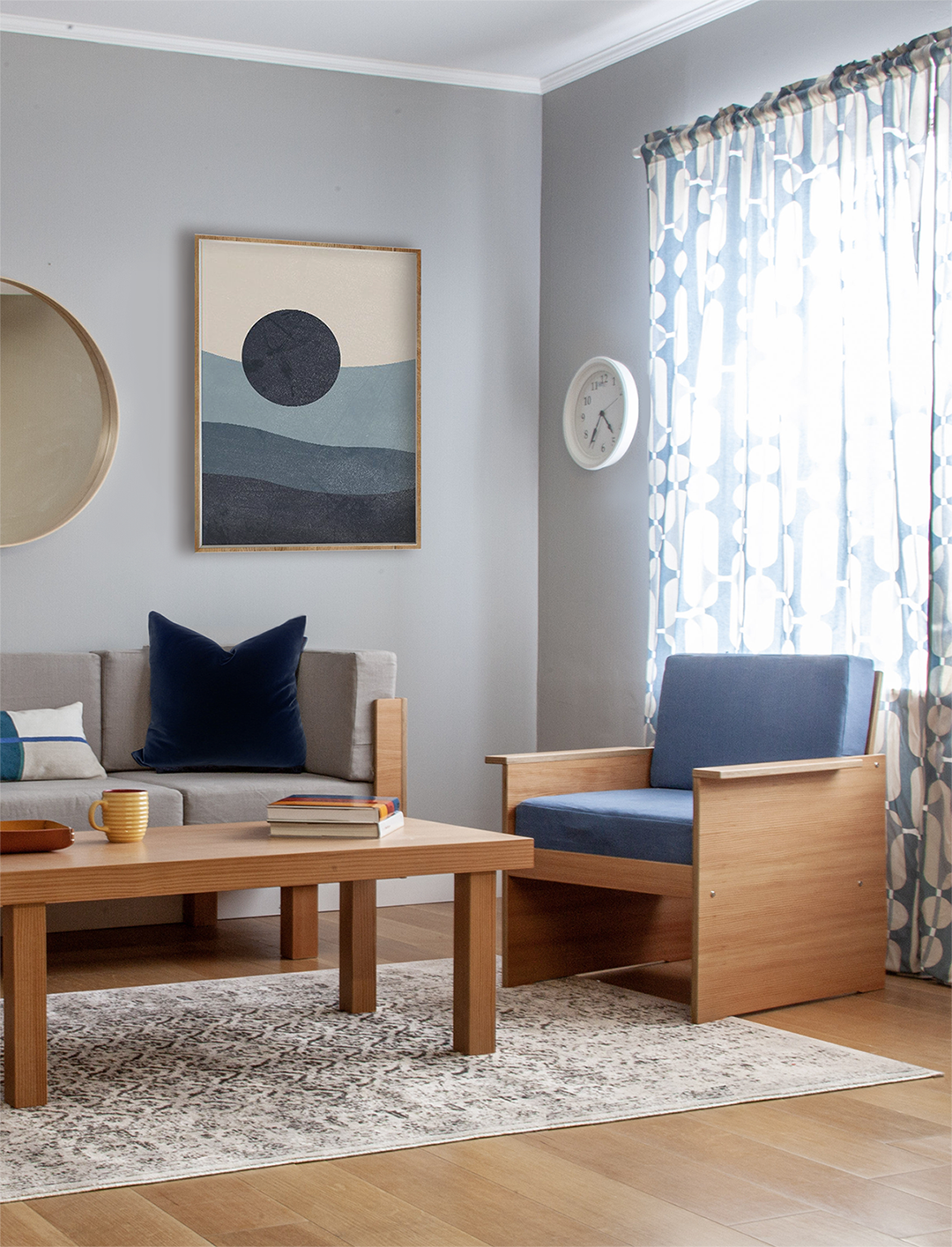 Stylish living area with wooden armchairs, a coffee table, geometric artwork, and a patterned rug.