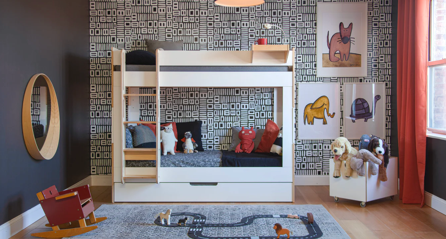 Children's room with bunk bed, toys, and decorative elements like patterned black and white wall paper, black walls, red curtains, and stuffed animal toys.