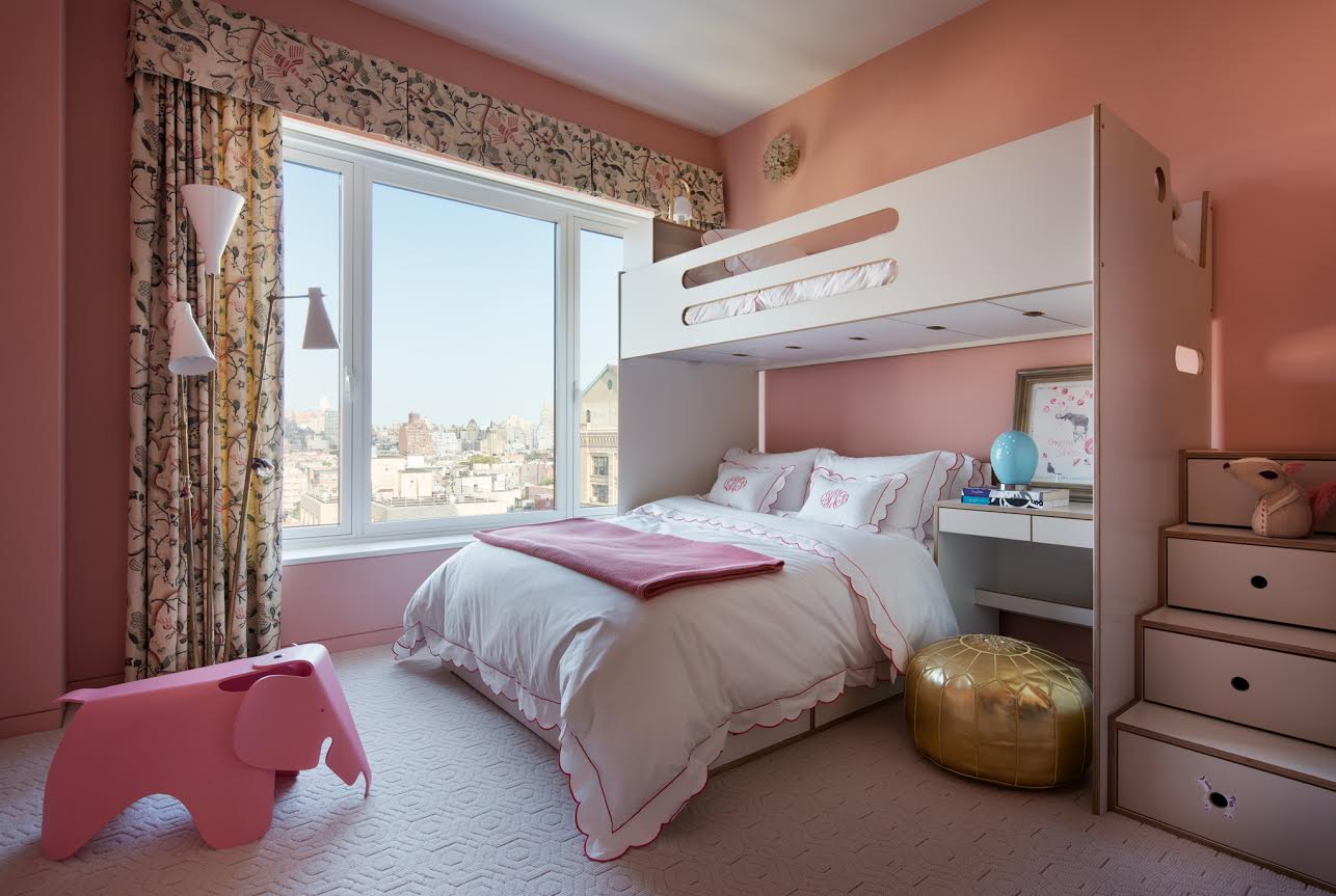 A kids' room with a pink theme, bunk bed, large window, floral curtains, pink elephant stool, and golden pouf.