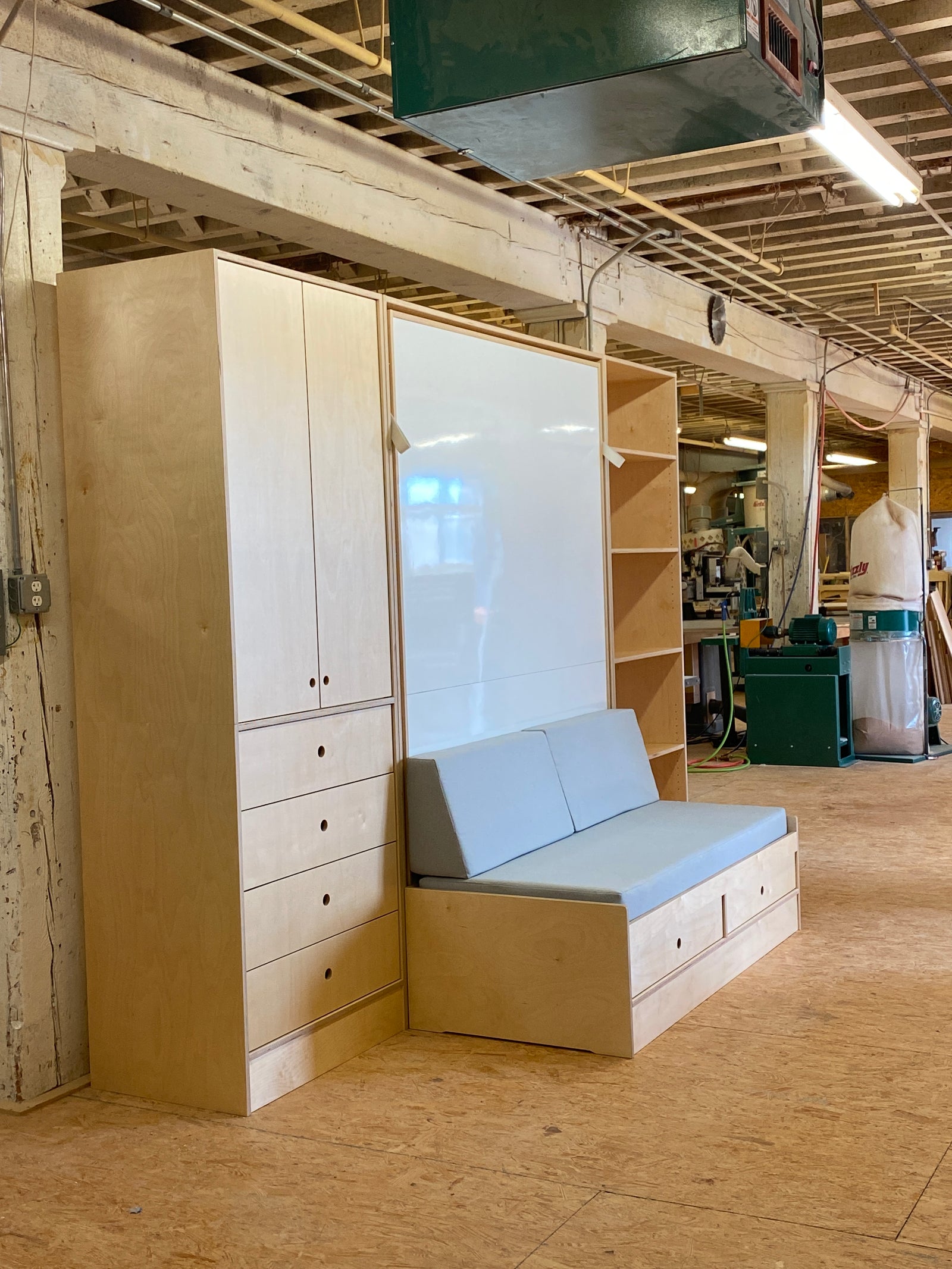 Workshop space with built-in wooden cabinets, a mirrored panel, and a bench with blue cushions.
