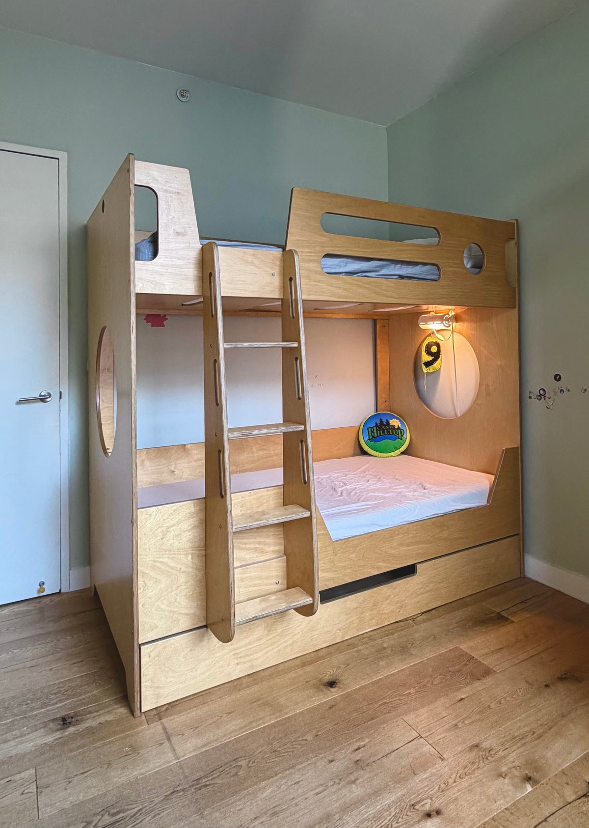 Pre-owned Marino bunk bed in birch at an angle, showing the ladder, round cutouts and lower bunk
