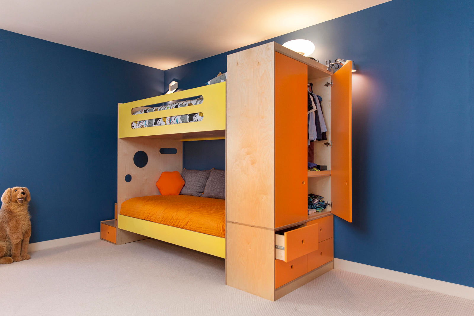 A yellow and orange loft bed with built-in storage and closet, set against a blue wall, with a dog sitting nearby.