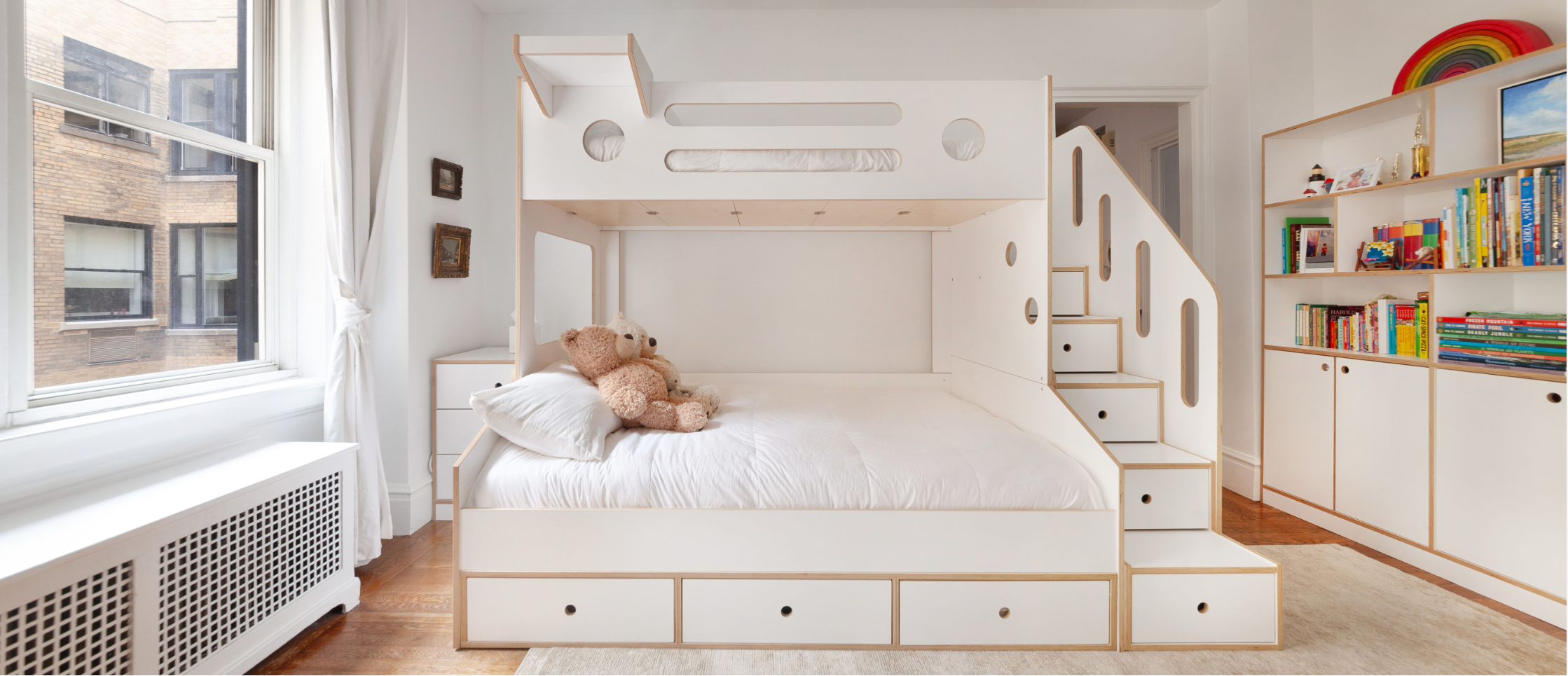 Children's bedroom with a bunk bed, teddy bear, and bookshelf.