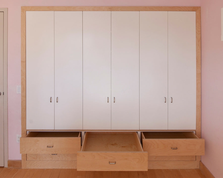 White wardrobe with open drawers, pink room walls.