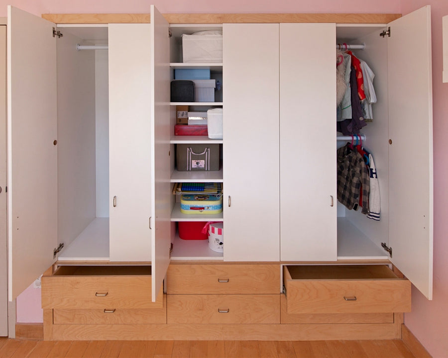 Open wardrobe with shelves, clothes, drawers in a pink room