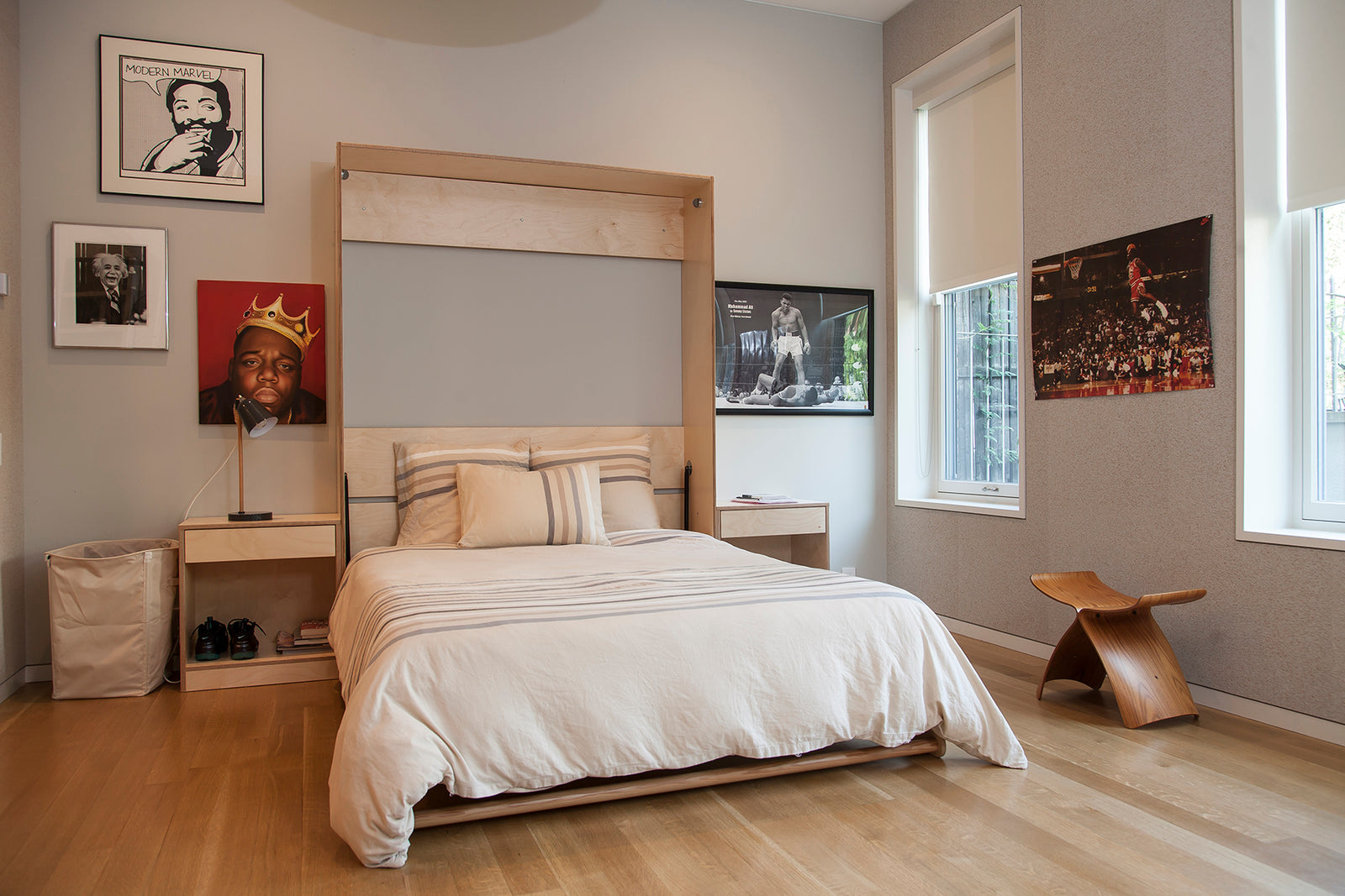 Artistic bedroom with a large bed, wooden floors, unique chair, and framed photographs on the walls.