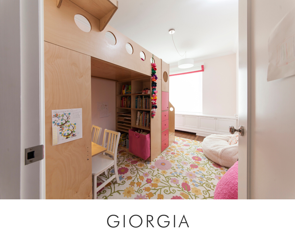 Giorgia room cozy room with a bed, colorful floral rug, bookshelf, and pink accents visible through the doorway.