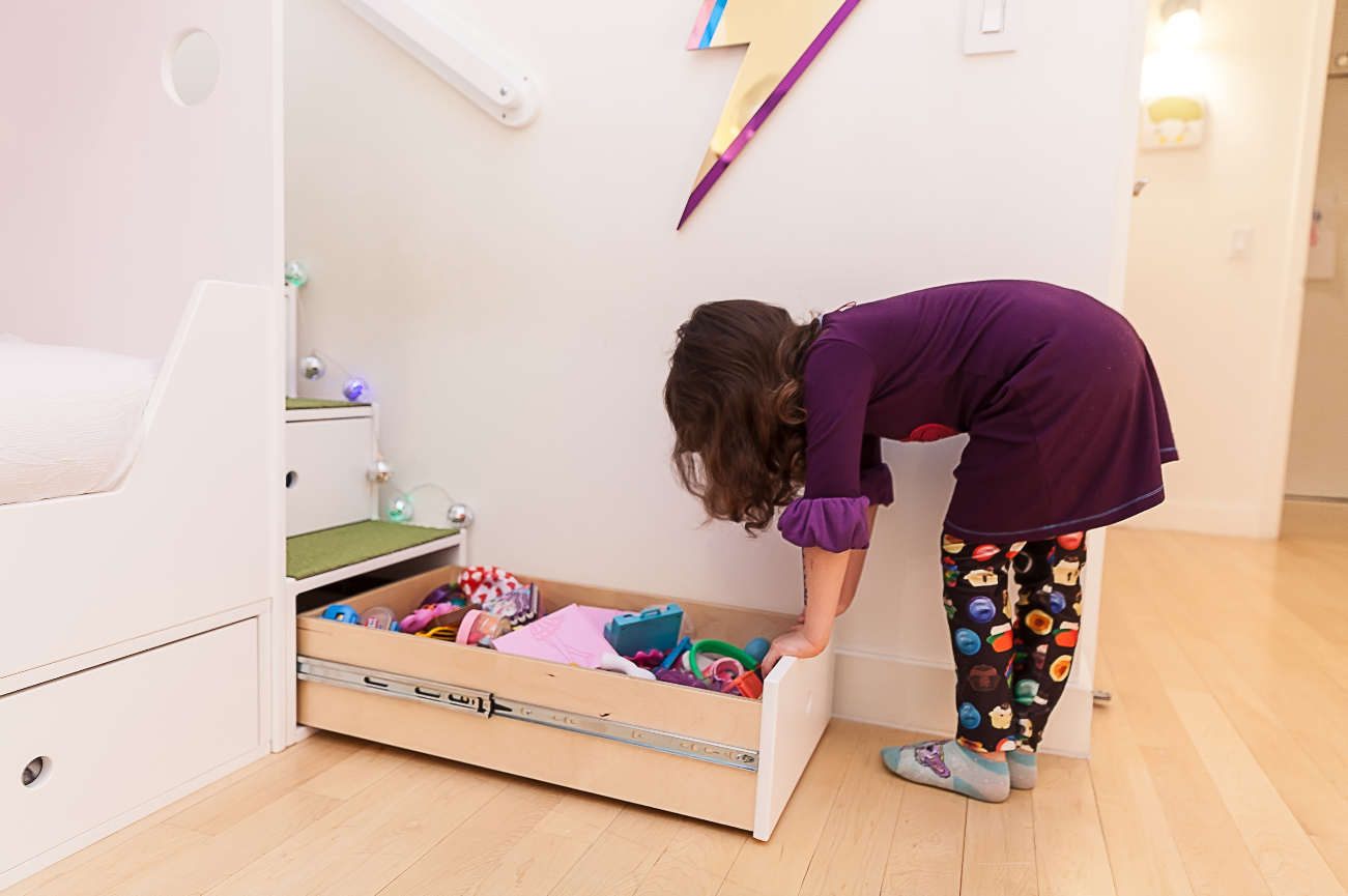 Child in colorful attire peering into an open drawer.