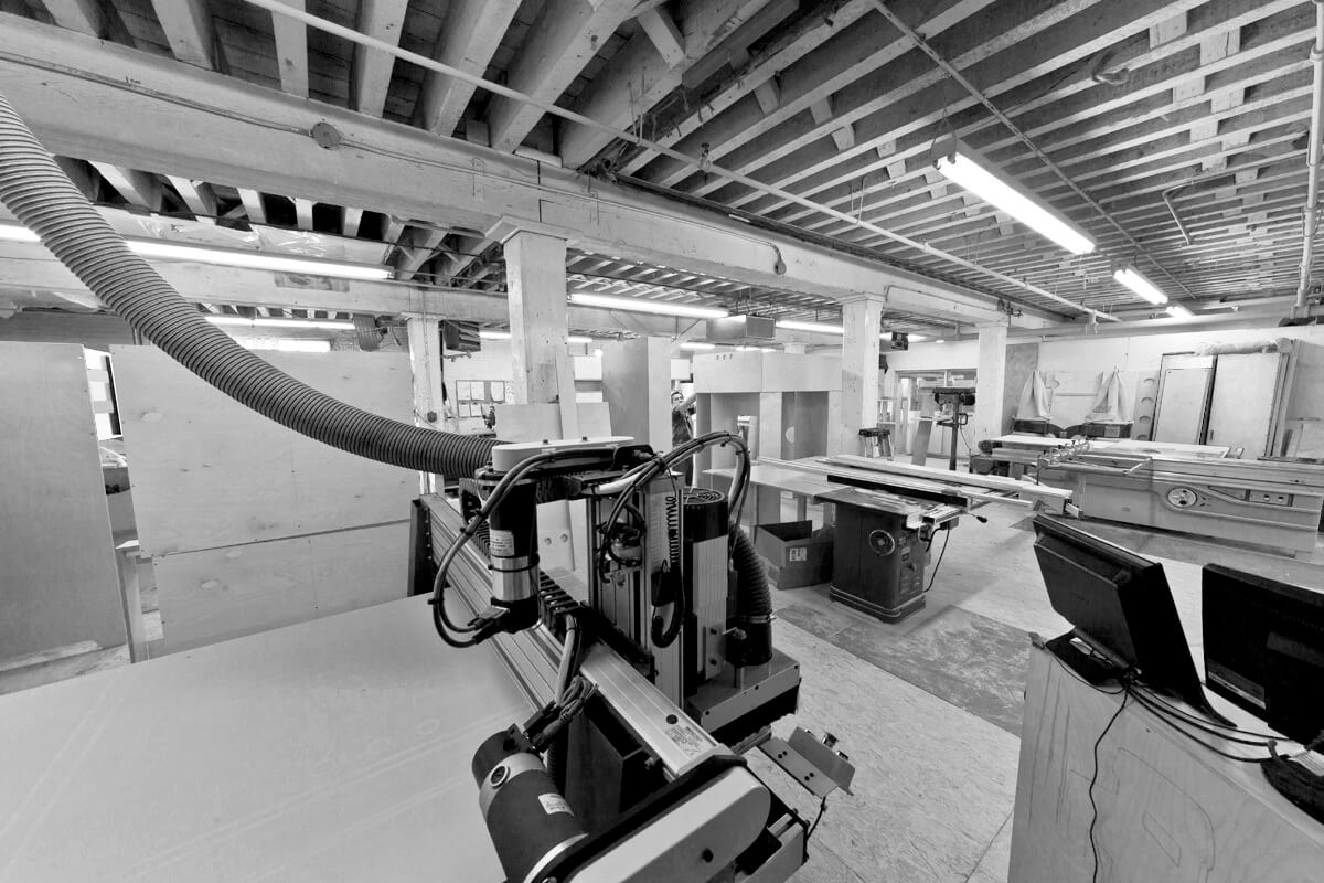 Black and white image of an industrial robot in a workshop with exposed ceiling beams.