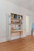 Compact desk with integrated shelving in a birch and white finish, featuring multiple open shelves and a functional workspace. Decorated with books, toys, and personal items, creating a versatile study area for a child’s bedroom.

