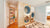 Custom birchwood playroom storage unit with built-in circular nooks lined with blue cushions, toy cubbies, cabinets, and a hidden bookcase door leading to an adjacent space