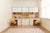 Double desk setup with white oak finish and white painted accents, featuring upper cabinets and open shelving for displaying toys and collectibles. Two matching wooden chairs are placed at the desks, providing a functional workspace for children.

