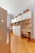 Dual desk setup with built-in shelving and drawers in a light birch and white finish. Organized workspace with upper cabinets, books, and decor baskets on top, creating a functional and aesthetic study area.

