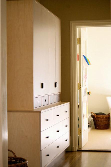Elegant storage solution featuring tall wooden cabinets and a white drawer unit in a sunlit hallway.