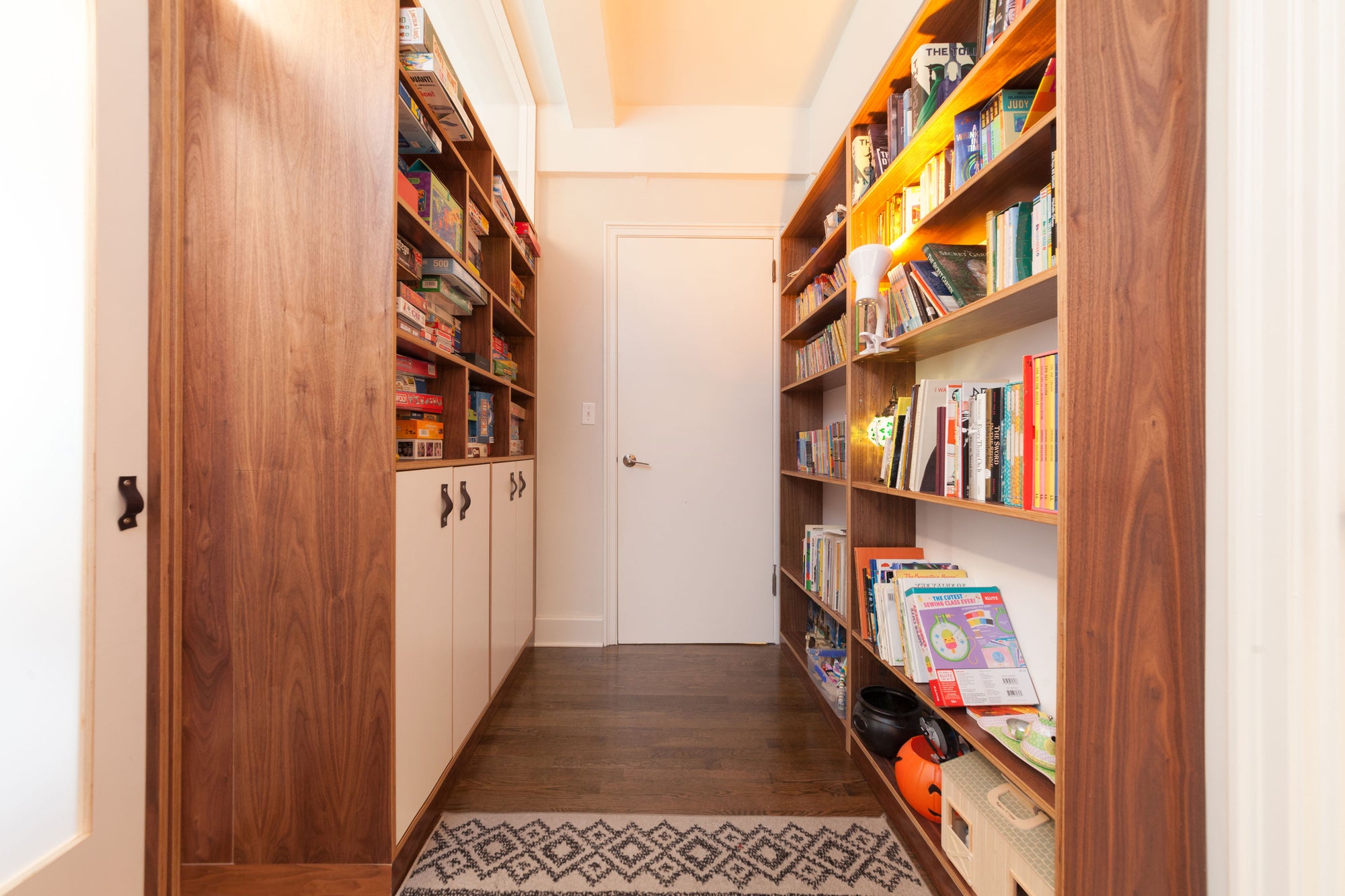 hallway of bookcase and storage units in walnut finish with white accents